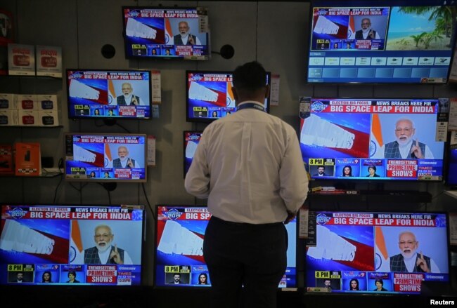 FILE - A salesman watches Prime Minister Narendra Modi addressing to the nation, on TV screens inside a showroom in Mumbai, India, March 27, 2019.