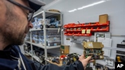 FILE - A worker of the Kyiv Scientific Research Institute of Forensic Expertise shows parts of Russian weapons in Kyiv, Ukraine, Oct. 15, 2024.