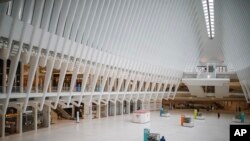 FILE - A pedestrian stands in a sparsely populated transit hub in the downtown financial district as retail stores remain shuttered because of COVID-19 concerns, March 21, 2020, in New York.