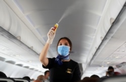 A flight attendant wearing a face mask sprays disinfectant inside a plane at Sharm el-Sheikh International Airport, Egypt, June 20, 2020.