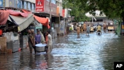 People wade through a flooded road during heavy monsoon rains in Hyderabad, Pakistan, on Aug. 30, 2024.