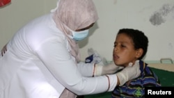 FILE - A pediatrician attends to a boy infected with diphtheria at the al-Sadaqa teaching hospital in the southern port city of Aden, Yemen, Dec. 18, 2017.
