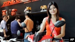 FILE - A model sits on a motor bike at a China-based Zongshen's booth during the Vietnam Auto Expo.