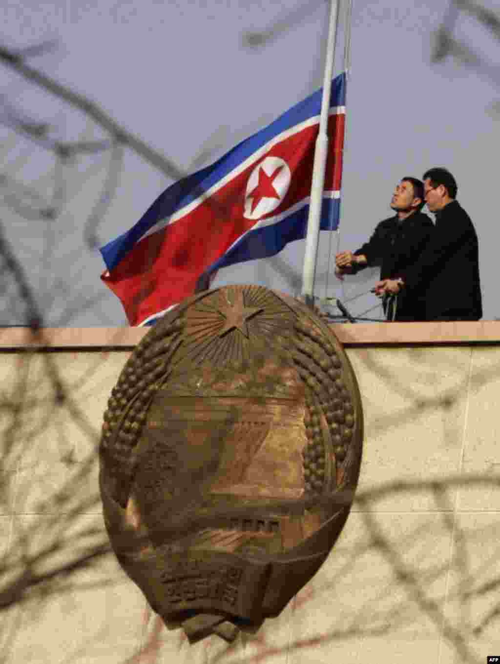 Nhân viên trên nóc đại sứ quán Bắc Triều Tiên tại Bắc Kinh treo cờ rũ sau khi có tin lãnh tụ qua đời. 19 tháng 12.