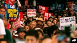 Protesters waving anti-war and anti-Shinzo Abe placards stage a rally in front of the Parliament building after a parliamentary committee approved legislation that would expand the role of Japan's military in Tokyo, July 15, 2015. 