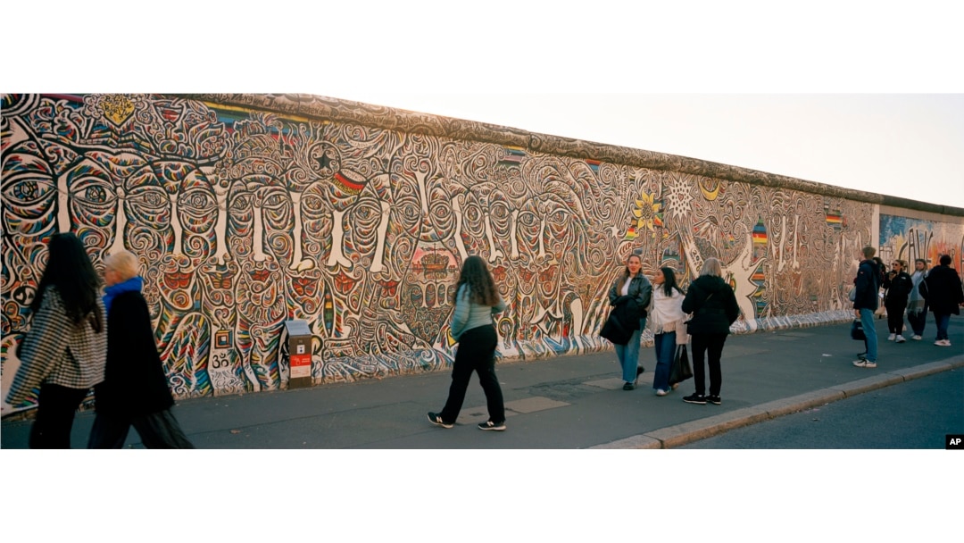 People gather at a painting at the so-called East Side Gallery, a popular place for street art on remains of the Berlin Wall in Berlin, Germany, on Oct. 15, 2024.