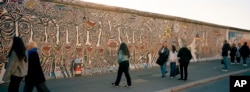 People gather at a painting at the so-called East Side Gallery, a popular place for street art on remains of the Berlin Wall in Berlin, Germany, on Oct. 15, 2024.