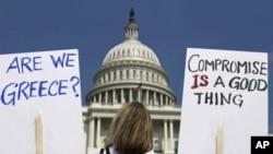 FILE - A demonstrator holds placards to protest U.S. debt in front of the U.S. Capitol in Washington, July 18, 2011.