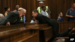 Oscar Pistorius, right, speaks with his uncle Arnold Pistorius, left, as he attends the fourth day of sentencing proceedings at the high court in Pretoria, South Africa, Oct. 16, 2014. 