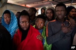 FILE - Migrants aboard the Golfo Azurro rescue vessel wait to be transferred to Italian authorities in Trapani harbor, on the Italian island of Sicily, Saturday, April 8, 2017.