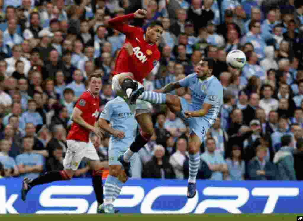 Manchester City's Carlos Tevez, right, competes for the ball with Manchester United's Chris Smalling during the English Premier League soccer match between Manchester City and Manchester United at the Etihad Stadium in Manchester, Monday, April 30, 2012.