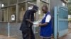 A police officer helps a worker to put on his gloves to protect himself from virus infection, July 31, 2012 at the Mulago Hospital in Kampala.