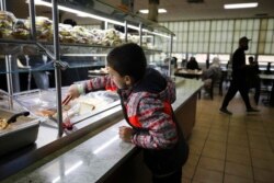 An Afghan refugee child reaches for a piece of bread during lunch hour at an eating facility in Liberty Village on Joint Base McGuire-Dix- Lakehurst in Trenton, N.J., Dec. 2, 2021.