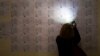 A woman uses the light of her cell phone to search for her name to vote, at a polling station during a parliamentary election in Yerevan, Armenia, April 2, 2017.