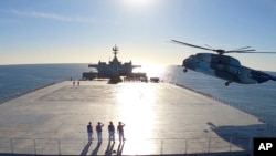 This image made from a video released on Jan. 13, 2021, by the Iranian Army shows a helicopter landing on Makran logistics vessel during a navy drill. 