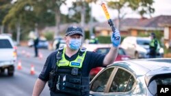 Un policier dirige la circulation à un barrage routier dans la banlieue de Melbourne, en Australie, le jeudi 2 juillet 2020. (Daniel Pockett / AAP Image via AP)