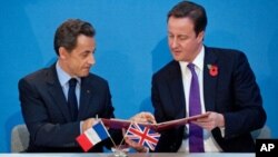 French President Nicolas Sarkozy (L), and British Prime Minister David Cameron exchange copies after signing a treaty during an Anglo-French summit at Lancaster House in central London, 2 Nov 2010