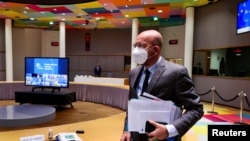 FILE - European Council President Charles Michel, wearing a protective mask, arrives for an EU Summit video conference, at the European Council building in Brussels, Belgium, Nov. 19, 2020.