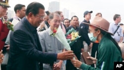 PM Kamboja Hun Sen (kiri) memberikan karangan bunga untuk seorang penumpang kapal pesiar MS Westerdam yang diperkenankan mendarat di pelabuhan Sihanoukville, Kamboja, Jumat, 14 Februari 2020. 