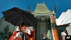 FILE - Gregg Donovan greets tourists on a warm day in Hollywood outside the TCL Chinese Theatre in Los Angeles, Oct. 2, 2014. The theater, which opened in 1927, is one of the first stops for tourists visiting Los Angeles.