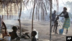 Children sit outside their family's tent as a neighbor bathes her son in a camp housing more than 2,600 Ivorian refugees, with more arriving daily, in Solo Town, near Zwedrou, Liberia, May 25, 2011.