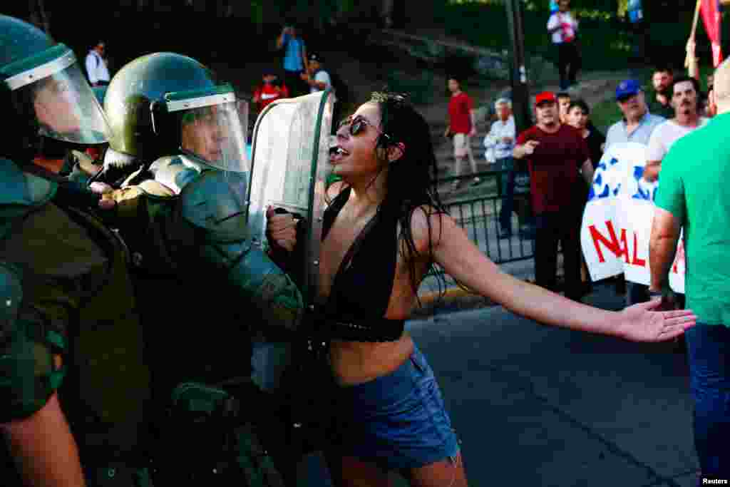 Seorang demonstran perempuan melabrak polisi anti huru-hara&nbsp;dalam aksi untuk mendukung nasionalisasi cadangan lithium di Santiago, Chile.