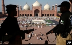 FILE - Pakistani policemen watch over worshippers praying at the Badshahi Mosque in Lahore, Pakistan, Oct. 16, 2013.