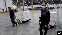 Boxes containing the Moderna COVID-19 vaccine are moved to the loading area for shipping at the McKesson distribution center in Olive Branch, Miss., Sunday, Dec. 20, 2020. (AP Photo/Paul Sancya, Pool)