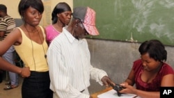 Warga di dekat Rundu, Namibia, mencelupkan jarinya di tinta setelah memberikan suara dalam pemilu (28/11). (AP/Dirk Heinrich)