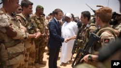 French President Emmanuel Macron, center, and Mali's President Ibrahim Boubacar Keita, center right, visit soldiers of Operation Barkhane, France's largest overseas military operation, in Gao, Northern Mali, May 19, 2017. 