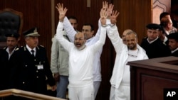 FILE - Cleric Safwat Hegazi (c), and Muslim Brotherhood leader Mohammed el-Beltagy (r) with other defendants gesture during an appearance in a courtroom in Cairo, Egypt.
