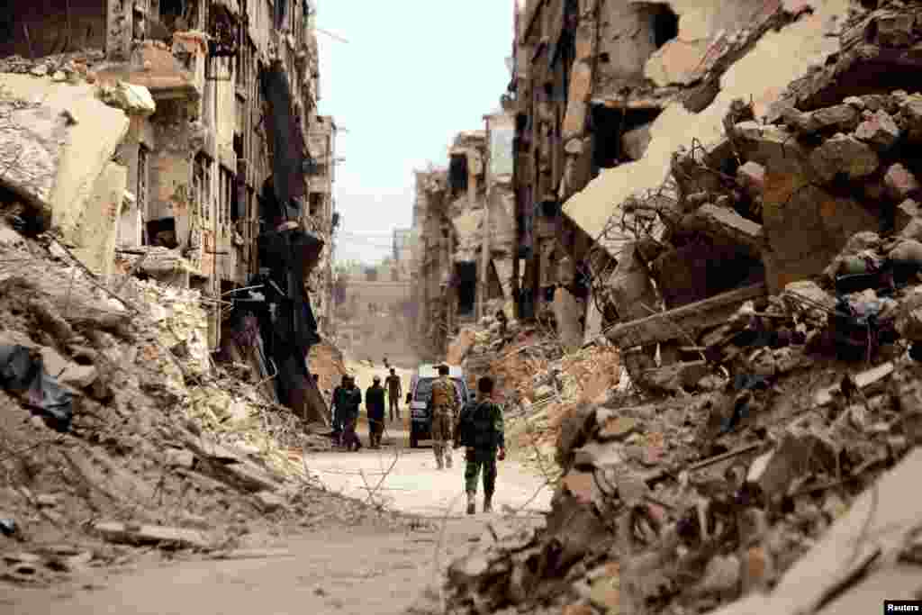 Soldiers walk past damaged buildings in Yarmouk Palestinian camp in Damascus, Syria.