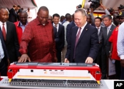 Kenyan President Uhuru Kenyatta, left, looks at a model of a locomotive with Chen Fenjian president of CCC during the unveiling of a cargo train at the Mombasa, Kenya.