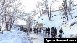 People walk along a road after a heavy snowfall in Murree, Pakistan, Jan. 8, 2022.