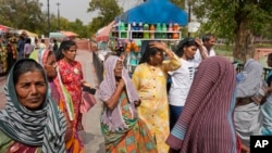  نئی دہلی میں شدید گرمی کے دوران پانی کی بوتلیں خریدتے ہوئے خواتین نے اپنے سروں کو ڈھکاہوا ہے ، فوٹو اے پی 18 جون 2024