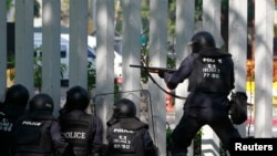 Polisi anti huru-hara menembakkan peluru karet dalam bentrokan dengan demonstran anti-pemerintah di stadion olahraga Bangkok (26/12). (Reuters/Chaiwat Subprasom) 