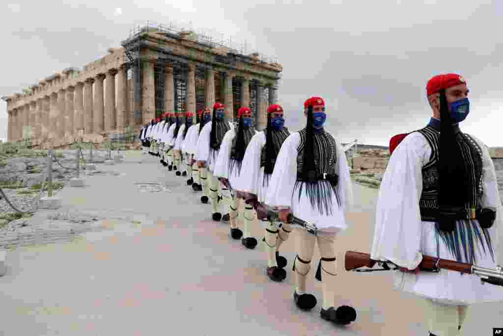 Members of the Presidential Guard walk in front of the Parthenon temple atop of Acropolis Hill after the Greek flag raising ceremony in Athens.