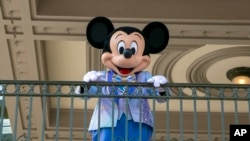 ARCHIVO - Un actor vestido como el Ratón Mickey saluda a los visitantes en la entrada del Parque Magic Kingdom en el Walt Disney World Resort, el 18 de abril de 2022, en Lake Buena Vista, Florida, EEUU.