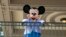 ARCHIVO - Un actor vestido como el Ratón Mickey saluda a los visitantes en la entrada del Parque Magic Kingdom en el Walt Disney World Resort, el 18 de abril de 2022, en Lake Buena Vista, Florida, EEUU.