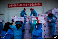 Para pekerja membawa kotak-kotak makanan laut saat mereka memuat truk pengangkut China. (Foto: AP)