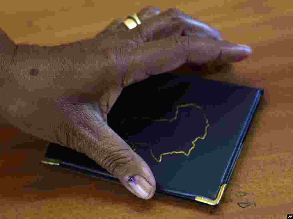 A woman, with her thumbnail marked with indelible ink to prove that she has voted at a polling station, picks up her identity book in Eden Park, south of Johannesburg, South Africa, May 7, 2014.