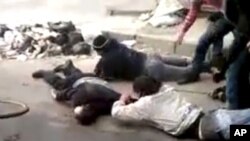 Men retrieve a body, in a rubbish-strewn street in Homs, Syria December 15, 2011.