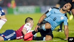 L’Uruguayen Luis Suarez, à droite, grimace après avoir été fauché dans la surface de réparation lors d’un match de la coupe du monde contre le Paraguay à Montevideo, Uruguay, 6 septembre 2016.