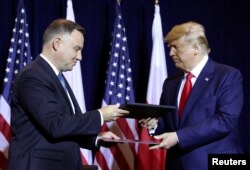 FILE - President Trump and Poland's President Andrzej Duda exchange documents after signing a "joint declaration enhancing defense cooperation" prior to a bilateral meeting on the sidelines of the U.N. General Assembly in New York, Sept. 23, 2019.