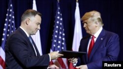 U.S. President Donald Trump and Poland's President Andrzej Duda exchange documents after signing a "joint declaration enhancing defense cooperation" prior to a bilateral meeting on the sidelines of the U.N. General Assembly in New York, Sept. 23, 2019.