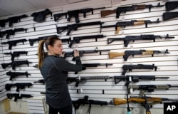 Gun shop owner Tiffany Teasdale-Causer returns a Ruger AR-15 semi-automatic rifle, the same model, though in gray rather than black, used by the shooter in a Texas church massacre two days earlier, to it's place on a wall with dozens of other semi-automatic rifles, Nov. 7, 2017, in Lynnwood, Washington.