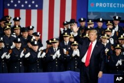 President Donald Trump waves after speaking to law enforcement officials on the street gang MS-13, July 28, 2017, in Brentwood, N.Y.