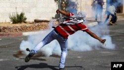 Palestinian protesters throw stones at Israeli soldiers, after the funeral of 22-year old Palestinian Issa al-Qatari, at the Amari refugee camp near the West Bank city of Ramallah.