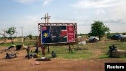 Civilians preparing to flee from renewed attacks gather in front of a sign celebrating the second anniversary of South Sudan's independence in Bentiu, Unity state of South Sudan, April 20, 2014.