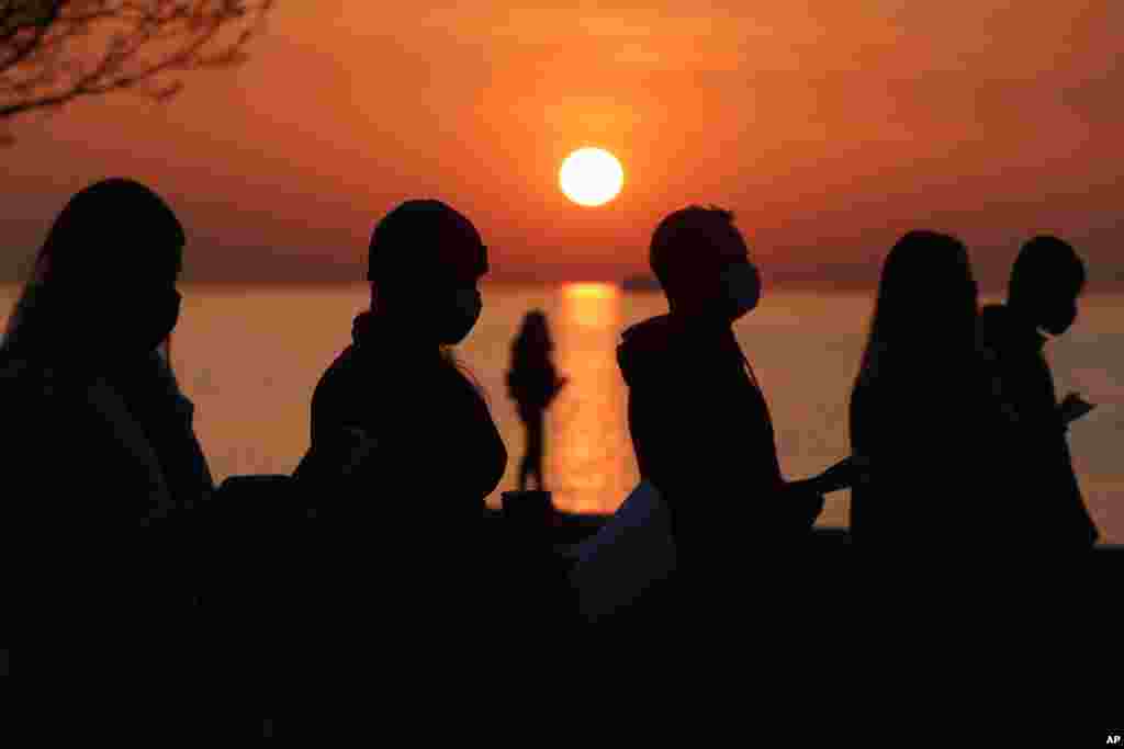 Parishioners are silhouetted against the rising sun as they pray during an Easter sunrise service held by Park Community Church at North Avenue Beach in Chicago, Illinois.